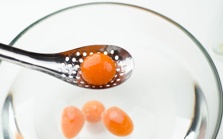 Carrot Orange Mango Spherification - removing spheres from rinsing bath